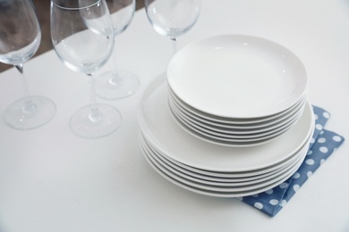 Stack of clean dishes and glasses on table in kitchen