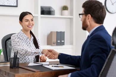Lawyer shaking hands with client in office, selective focus