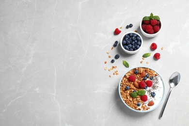 Photo of Healthy homemade granola with yogurt and berries served on light grey table, flat lay. Space for text