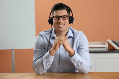 Photo of Man with headset holding online webinar indoors, view from webcam