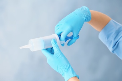Photo of Doctor in medical gloves with large syringe on color background