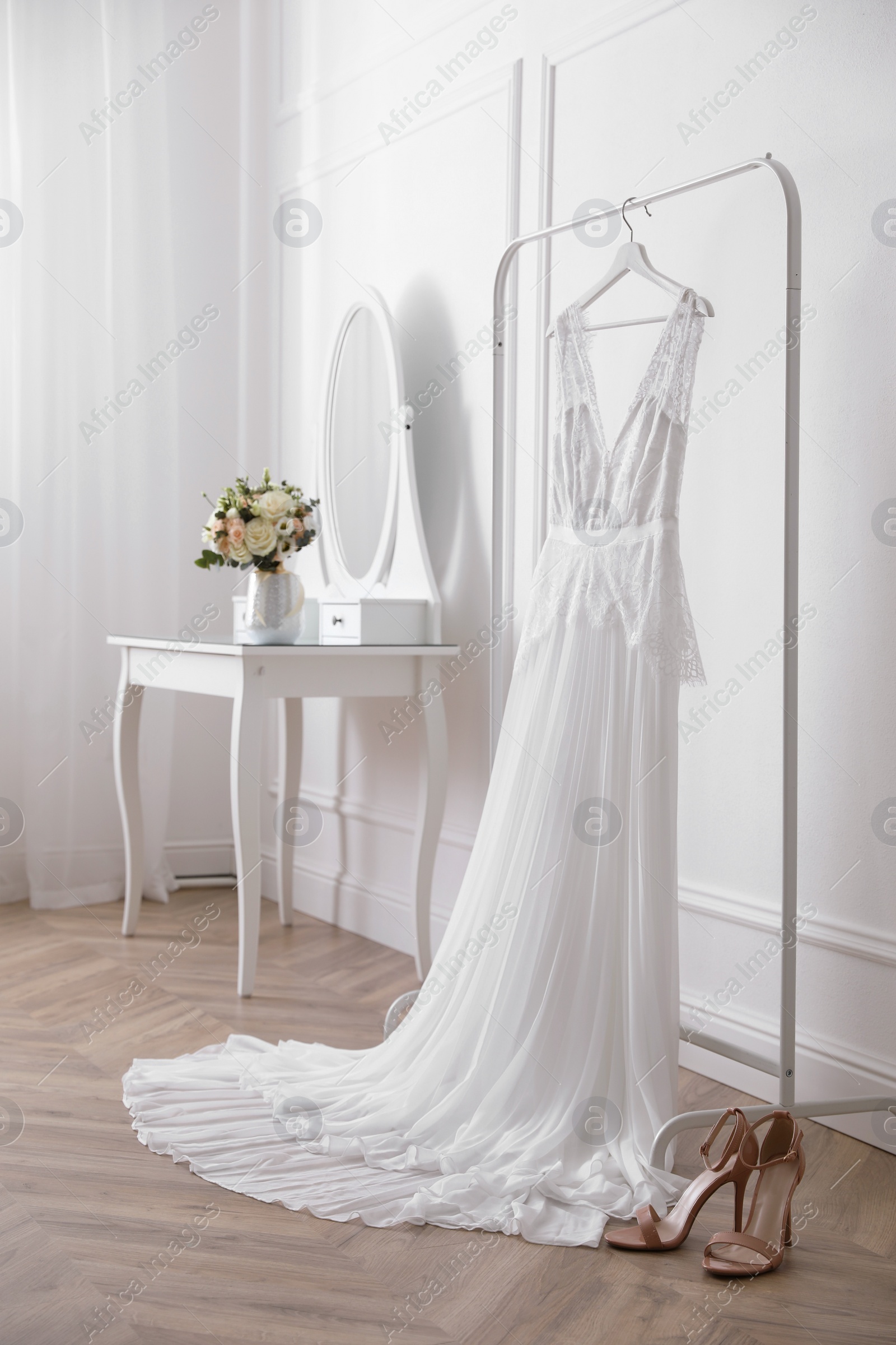 Photo of Elegant wedding dress hanging on rack indoors