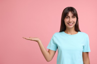 Special promotion. Happy woman showing something on pink background, space for text