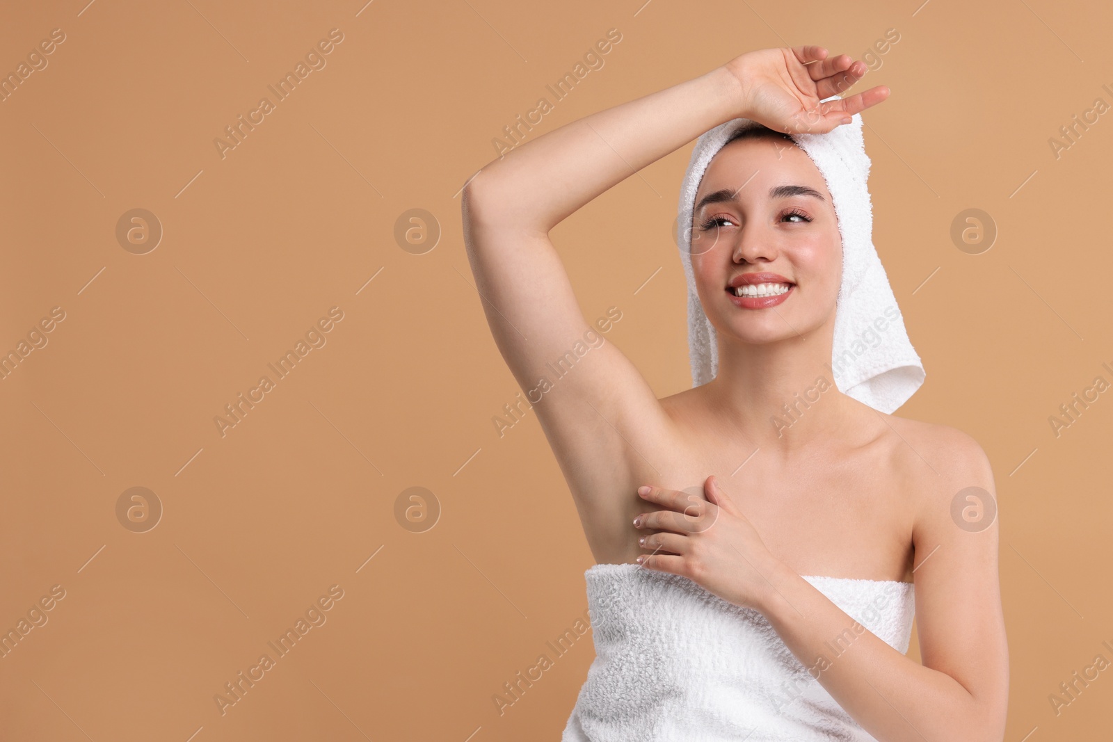 Photo of Beautiful woman showing armpit with smooth clean skin on beige background, space for text