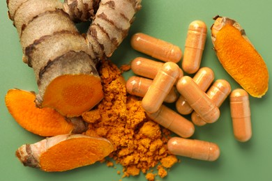 Aromatic turmeric powder, pills and raw roots on green background, flat lay