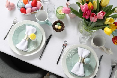 Photo of Festive Easter table setting with beautiful flowers and painted eggs, top view