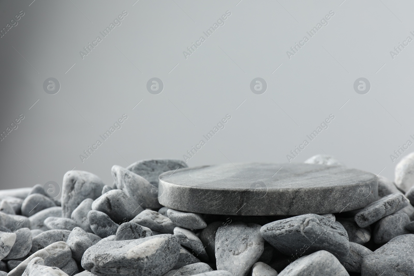 Photo of Presentation for product. Stone and pebbles on grey background. Space for text