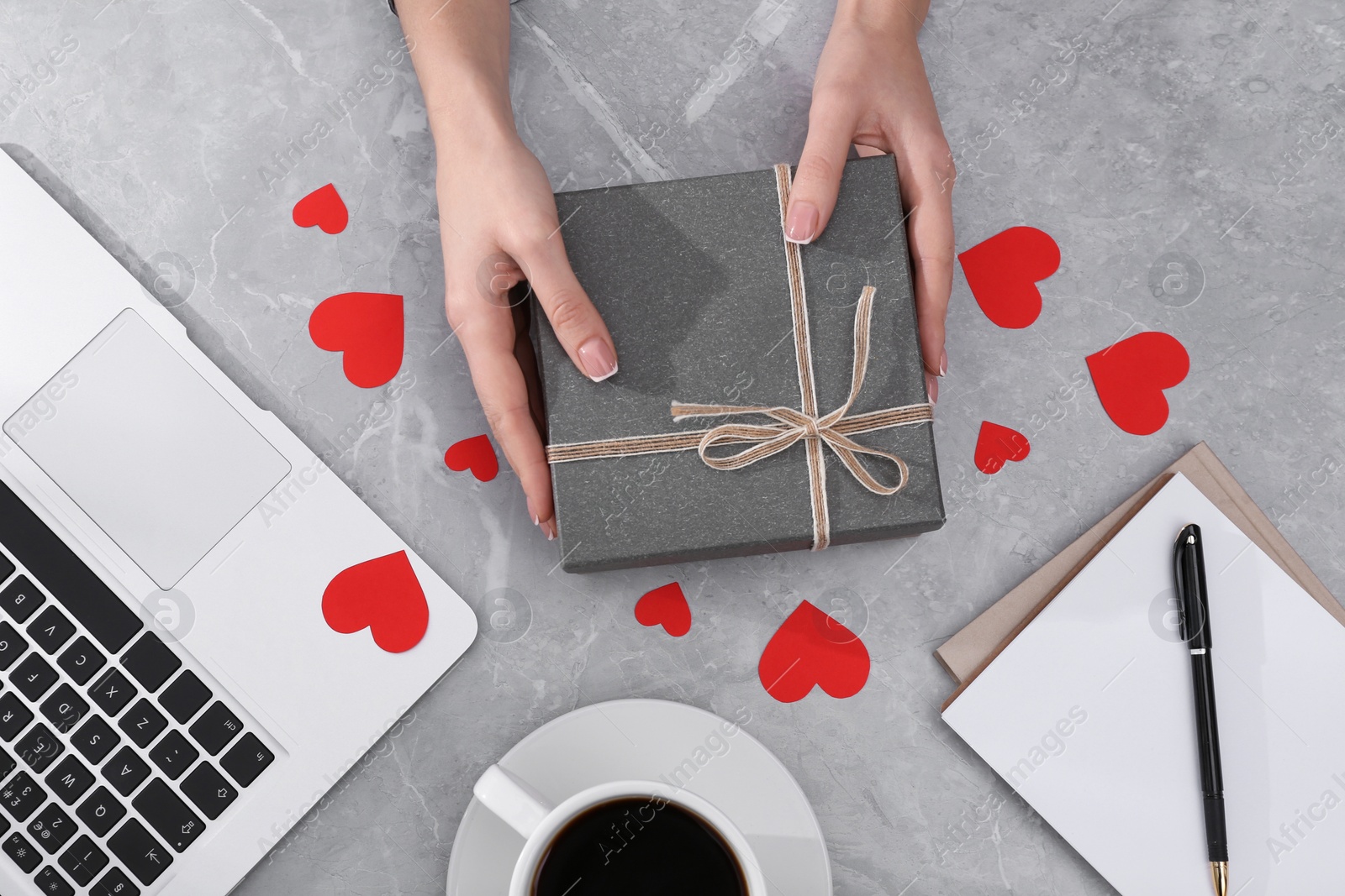 Photo of Woman with gift box at light grey marble table, flat lay. Valentine's day celebration