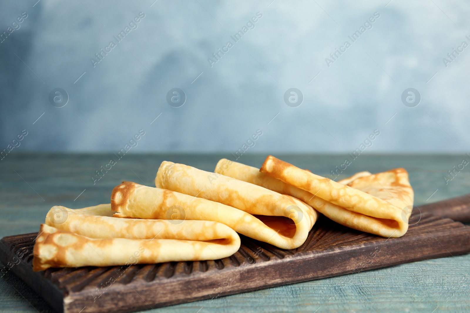 Photo of Fresh thin pancakes on blue wooden table
