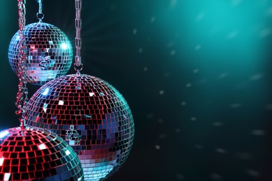 Photo of Shiny disco balls under bright cyan light, space for text