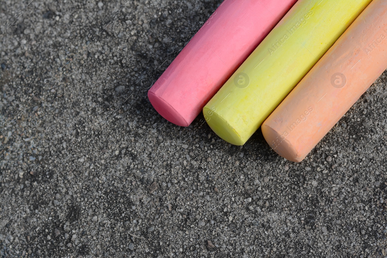 Photo of Colorful chalk sticks on asphalt, flat lay. Space for text