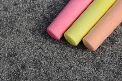 Photo of Colorful chalk sticks on asphalt, flat lay. Space for text