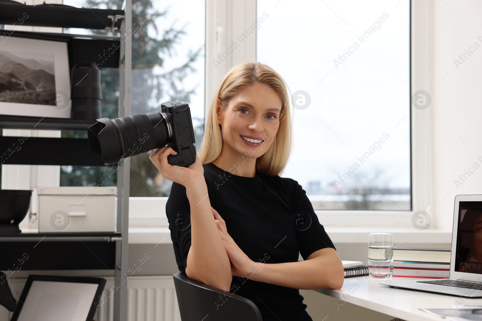 Photo of Professional photographer with digital camera at table in office