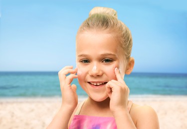 Sun protection. Cute girl applying sunblock onto face on beach