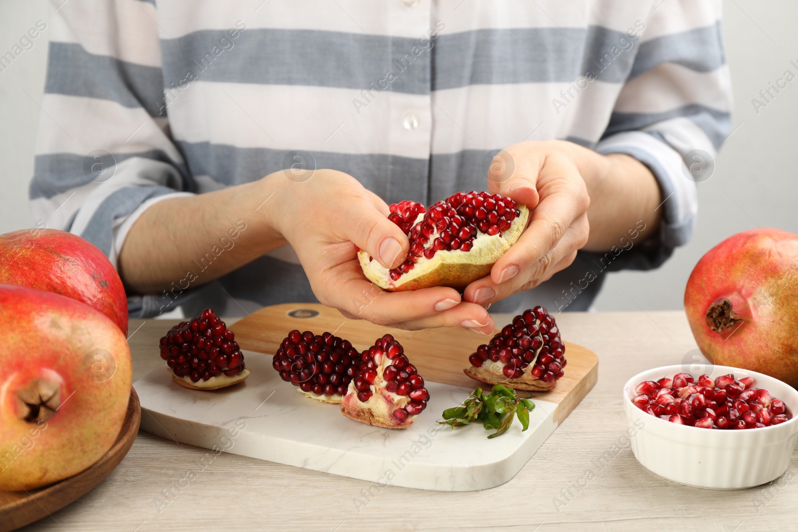 Photo of Woman with delicious ripe pomegranate at wooden table, closeup