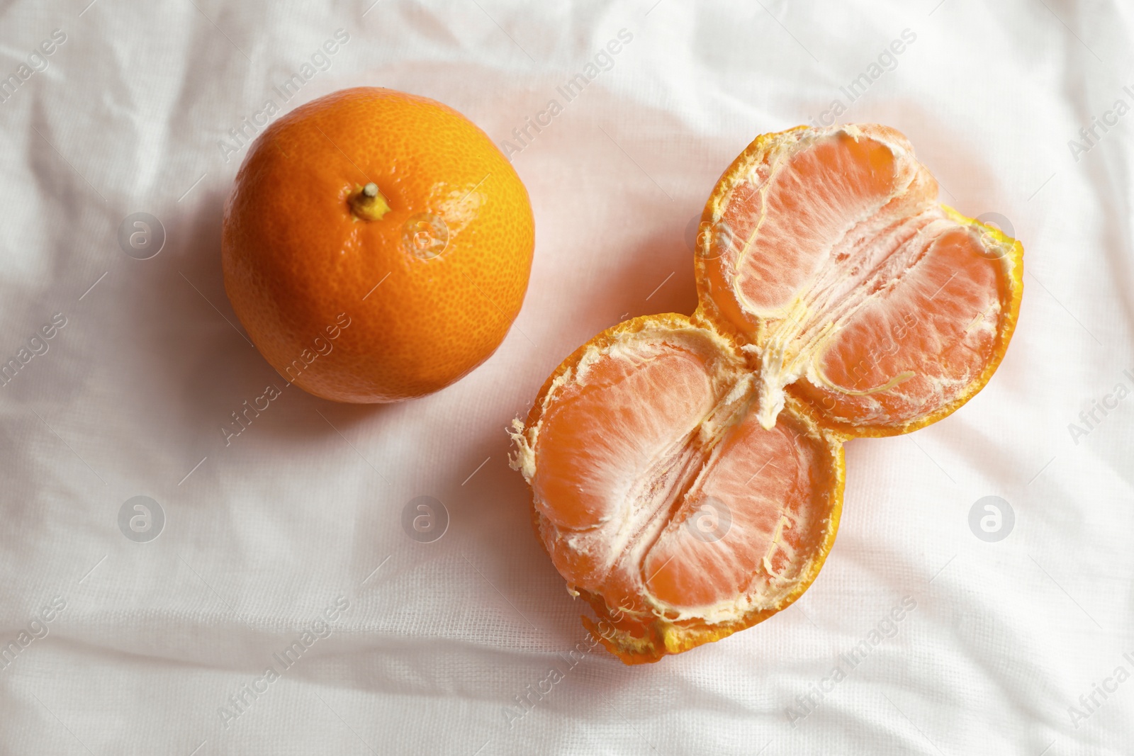 Photo of Fresh ripe tangerines on white cloth, flat lay