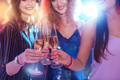 Young women chinking glasses in nightclub, closeup. Birthday party