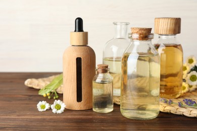 Aromatherapy. Different essential oils and flowers on wooden table