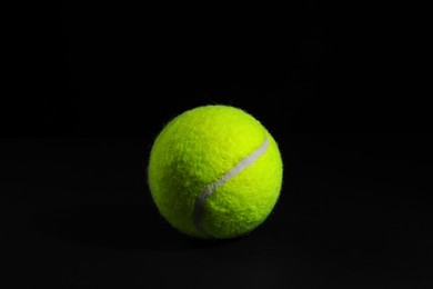 Photo of One bright tennis ball on black background