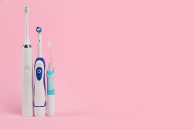 Photo of Electric toothbrushes on pink background, space for text