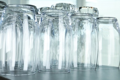 Photo of Empty glasses on grey table against blurred background, closeup