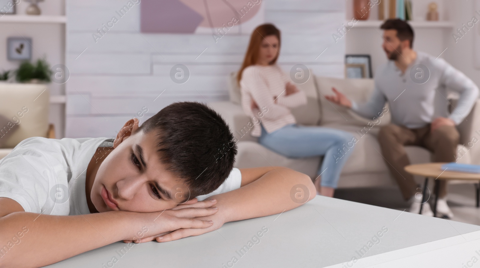 Photo of Couple arguing at home, focus on their unhappy teenage boy. Problems in family