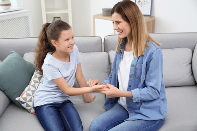 Photo of Young woman checking little girl's pulse indoors