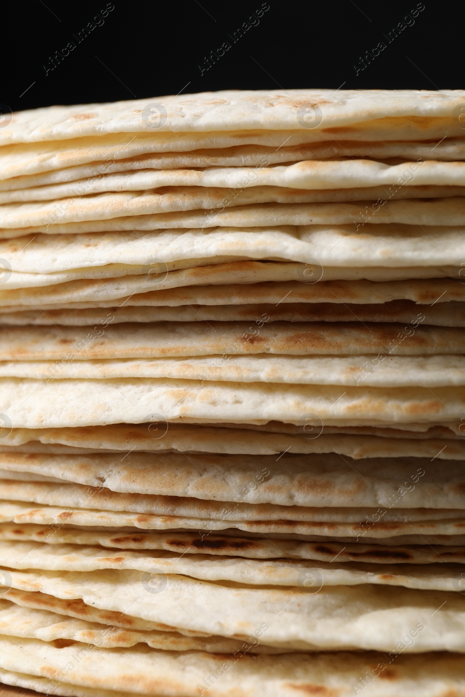 Photo of Stack of tasty tortillas on black background, closeup