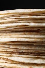 Stack of tasty tortillas on black background, closeup