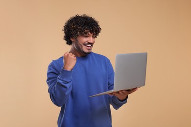 Smiling man with laptop on beige background