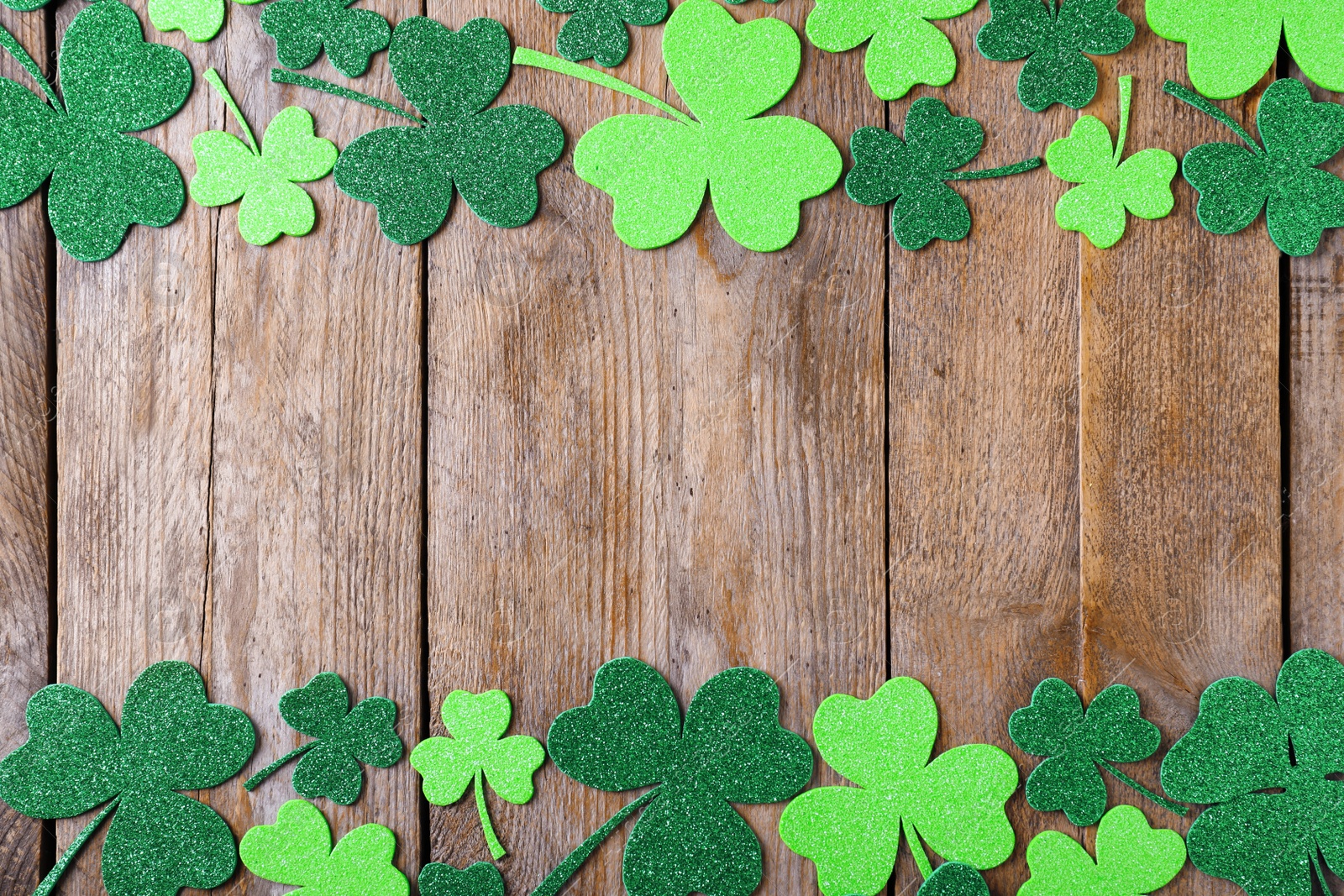 Photo of Frame made of clover leaves on wooden table, flat lay with space for text. St. Patrick's Day celebration