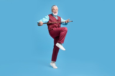 Emotional senior man with walking cane on light blue background