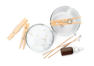 Photo of Wax flakes, wicks, clothespins and essential oil on white background, top view. Making homemade candle