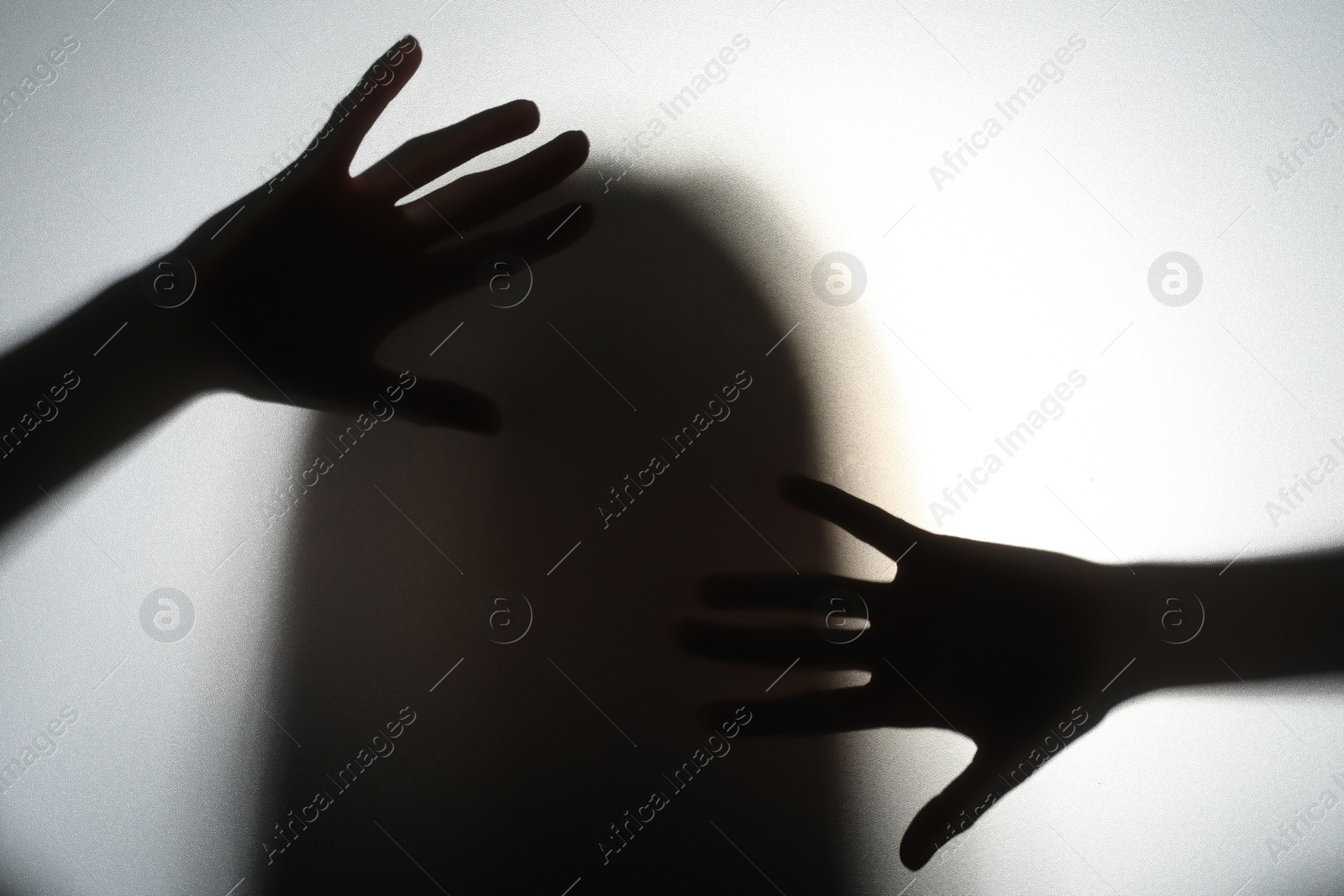 Photo of Silhouette of creepy ghost behind glass against white background