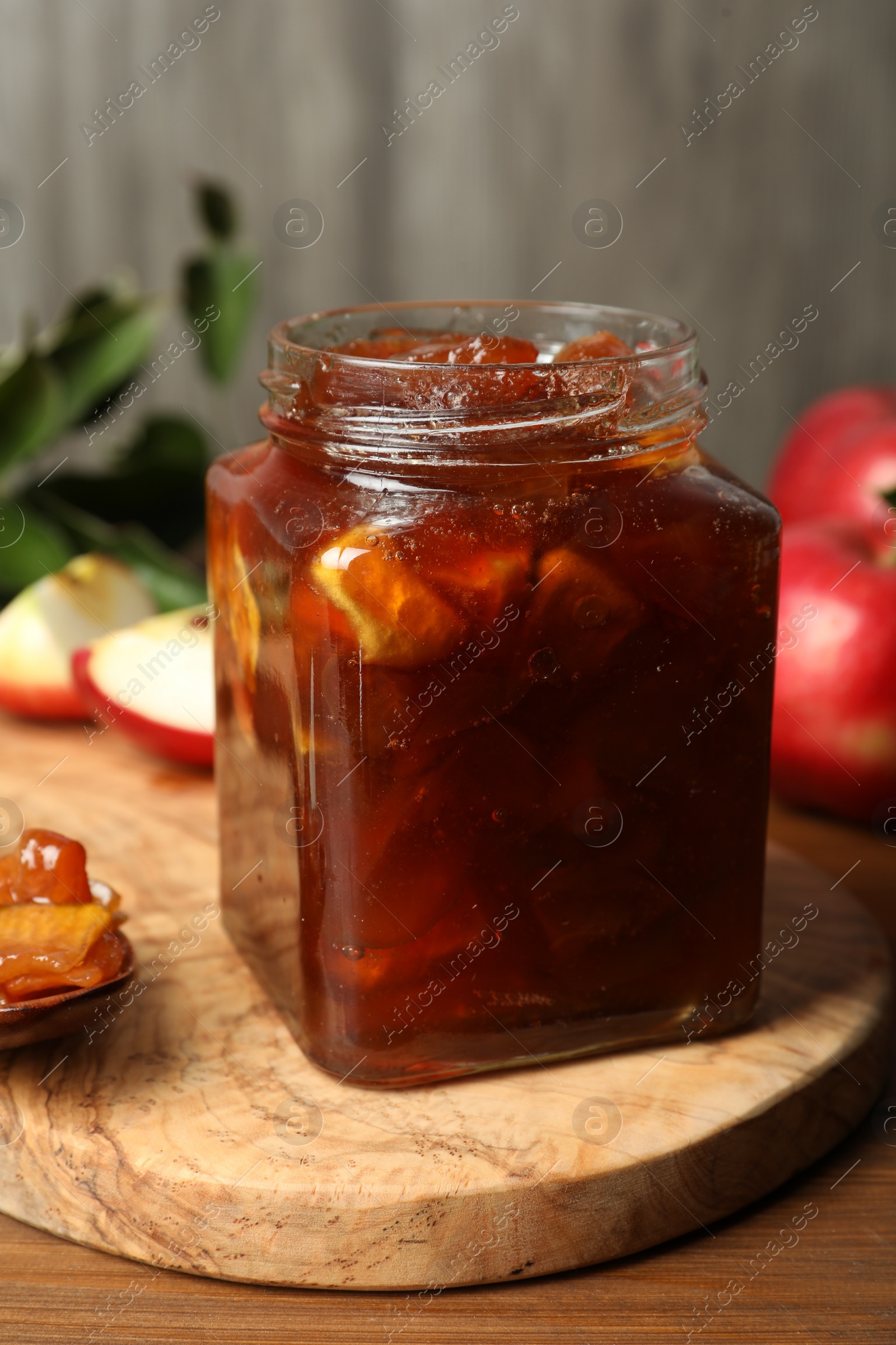 Photo of Tasty apple jam in glass jar on wooden table, closeup