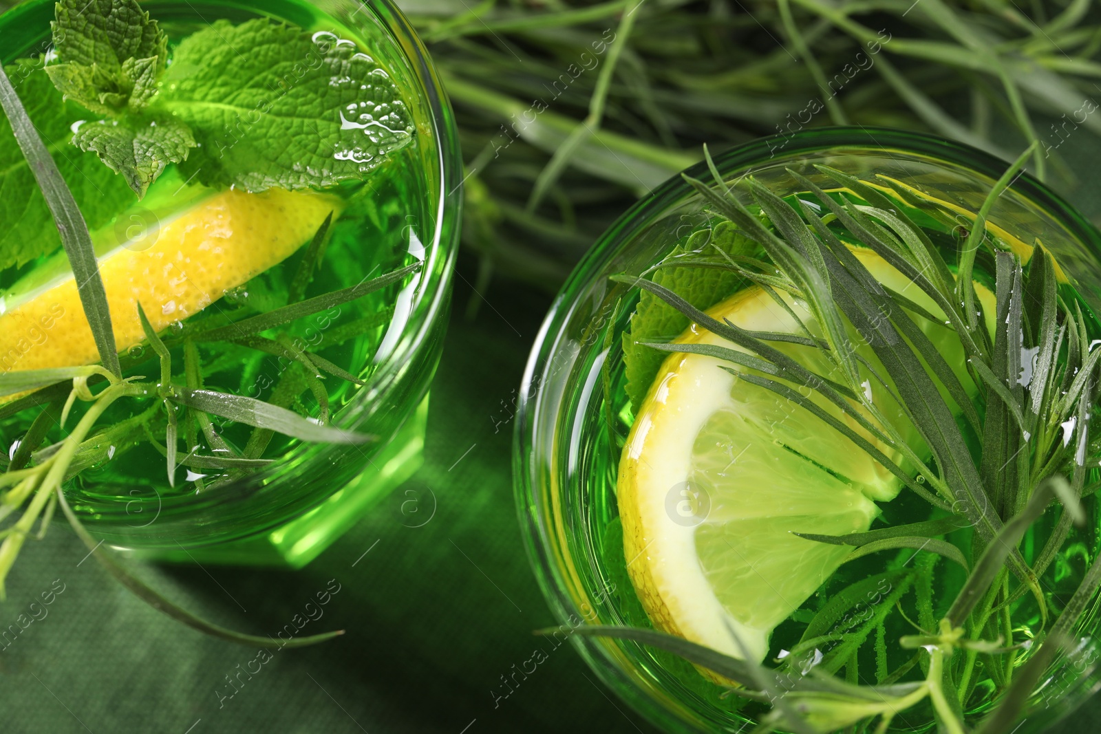 Photo of Glasses of refreshing tarragon drink with lemon slices on table, flat lay