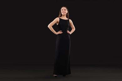 Beautiful young woman in elegant dress on black background