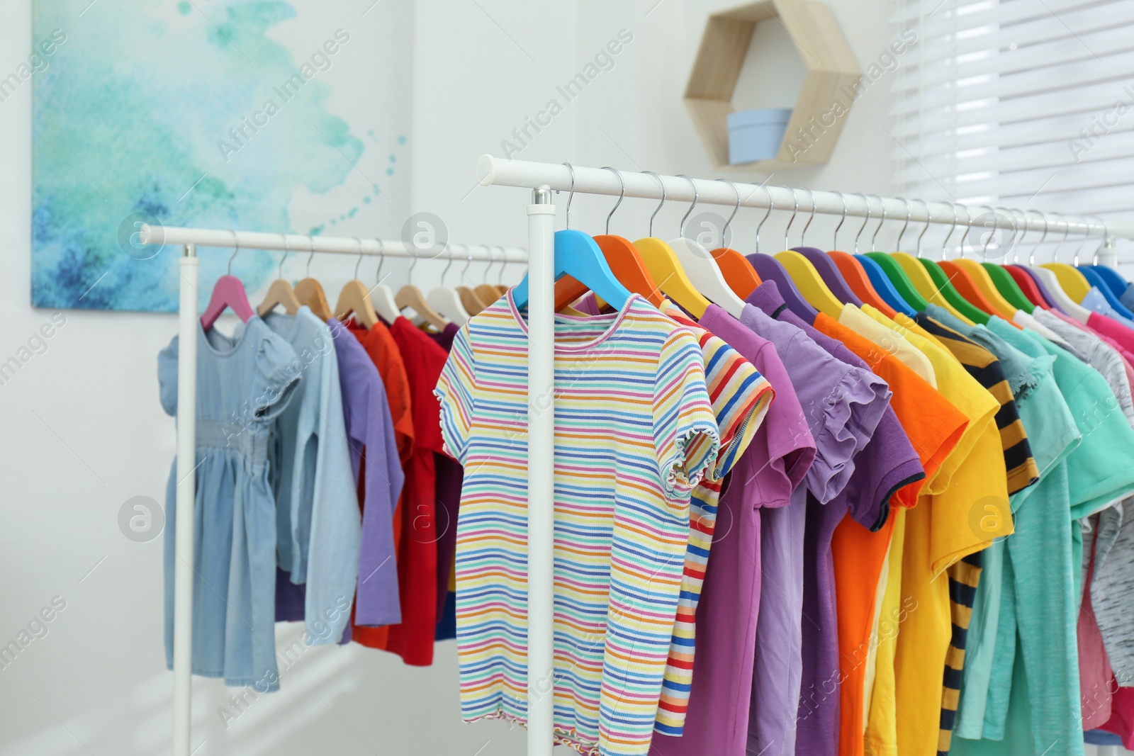 Photo of Different child's clothes hanging on racks indoors