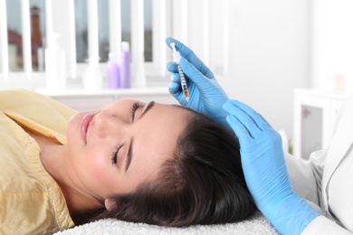 Photo of Young woman with hair loss problem receiving injection in salon