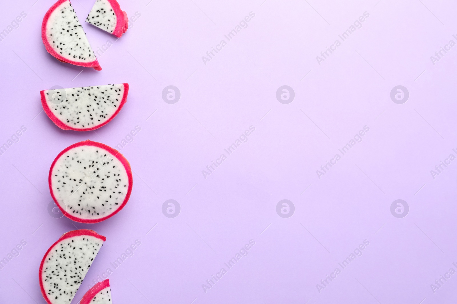 Photo of Slices of delicious dragon fruit (pitahaya) on violet background, flat lay. Space for text