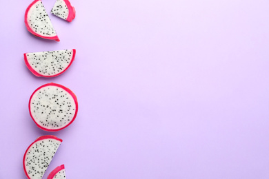 Photo of Slices of delicious dragon fruit (pitahaya) on violet background, flat lay. Space for text