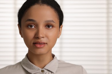 Portrait of beautiful woman looking at camera indoors. Space for text