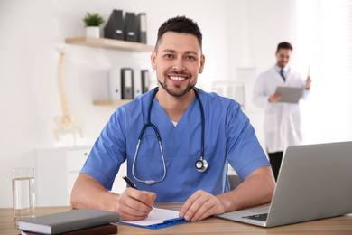 Portrait of male doctor at table in modern clinic