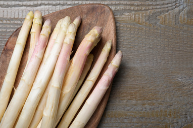 Photo of Fresh white asparagus on wooden table, top view. Space for text