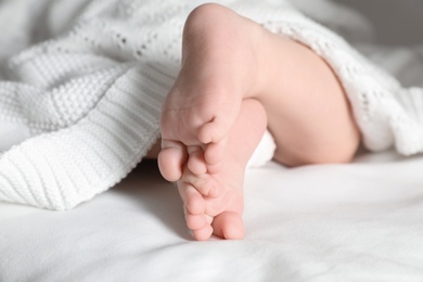 Photo of Little baby with cute feet lying on bed, closeup