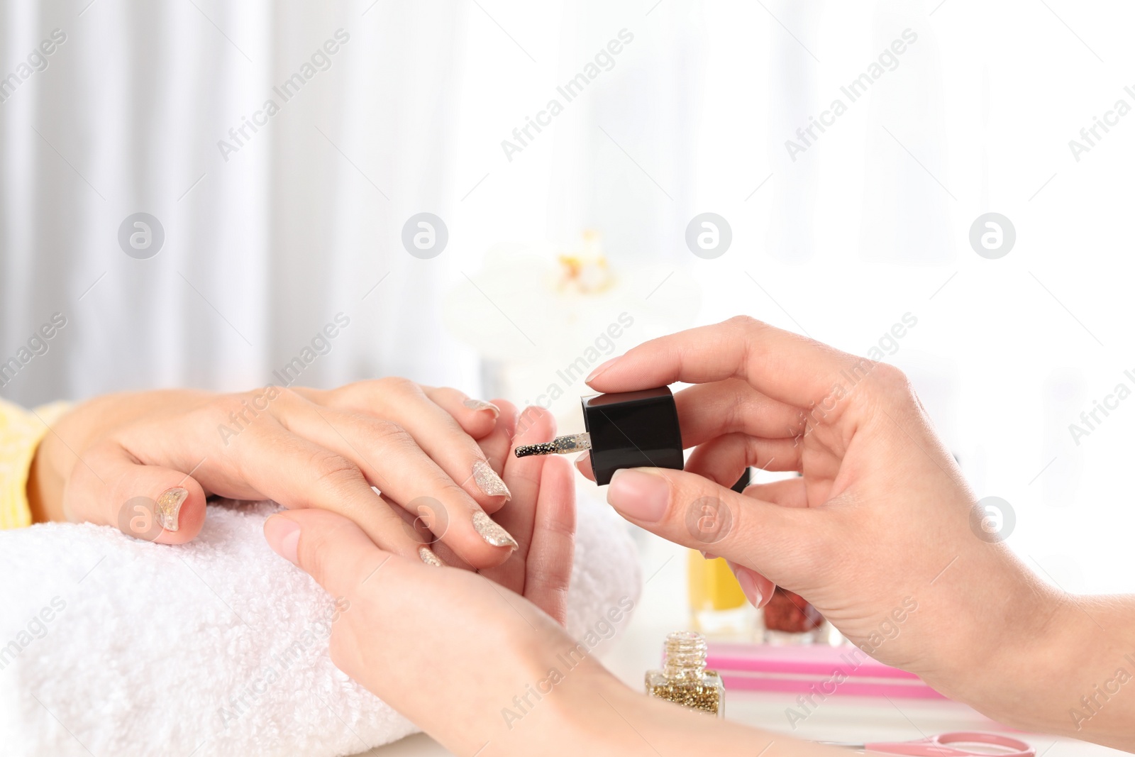 Photo of Manicurist painting client's nails with polish in salon, closeup