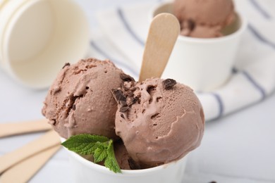 Photo of Paper cup with tasty chocolate ice cream on white table, closeup