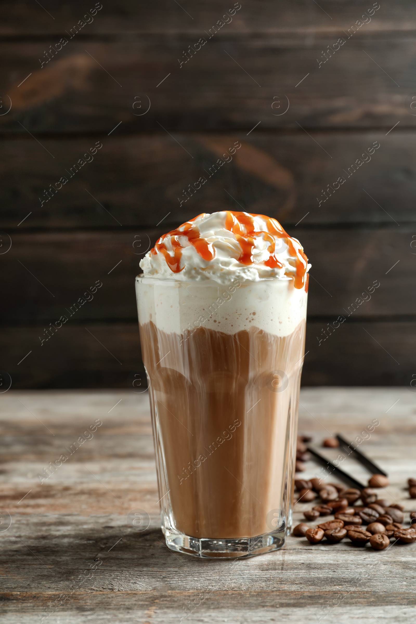 Photo of Glass of coffee with caramel topping on wooden table