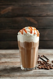 Glass of coffee with caramel topping on wooden table