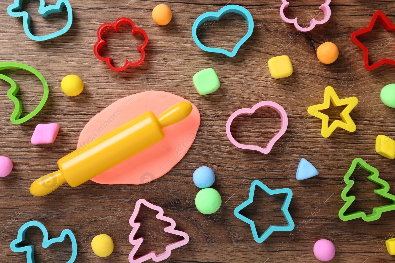 Photo of Different color play dough with molds on wooden table, flat lay